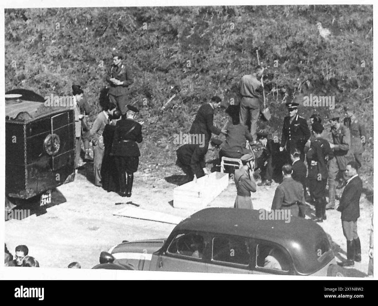 Il corpo di un ex capo della polizia fascista viene rimosso da una sedia e messo in una bara sotto la supervisione dell'esercito britannico. Foto Stock