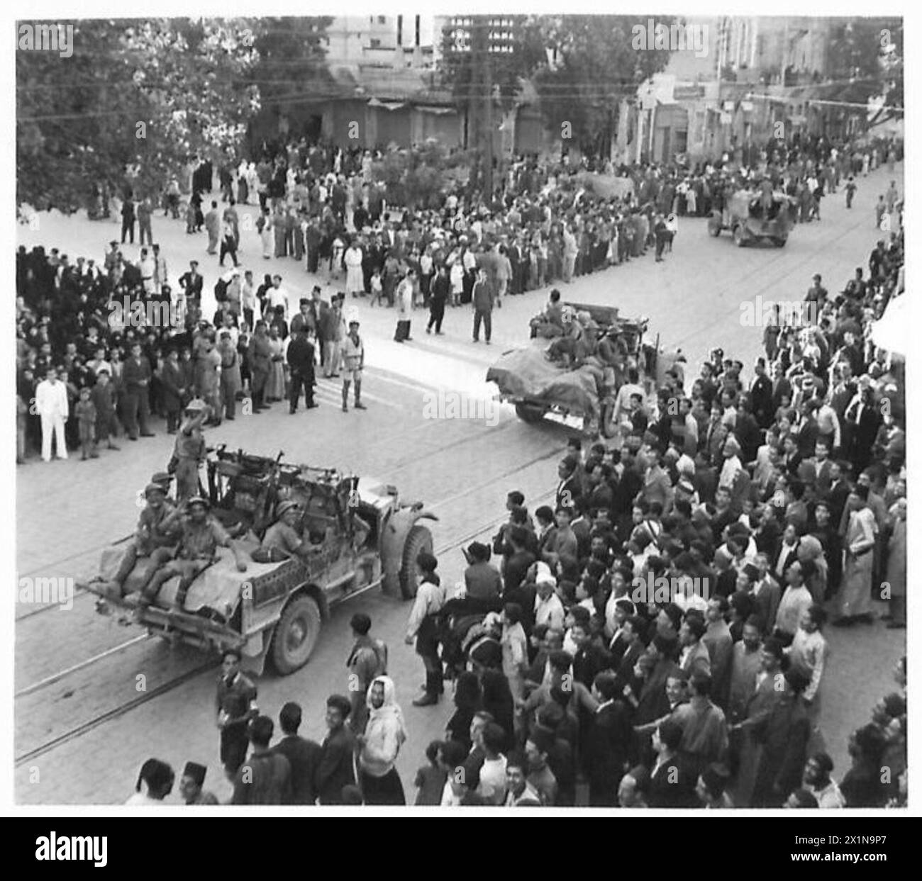 Gli abitanti locali di Damasco osservano i trasporti britannici e francesi liberi e le truppe si muovono per le strade durante la cattura della città, come documentato dall'esercito britannico. Foto Stock