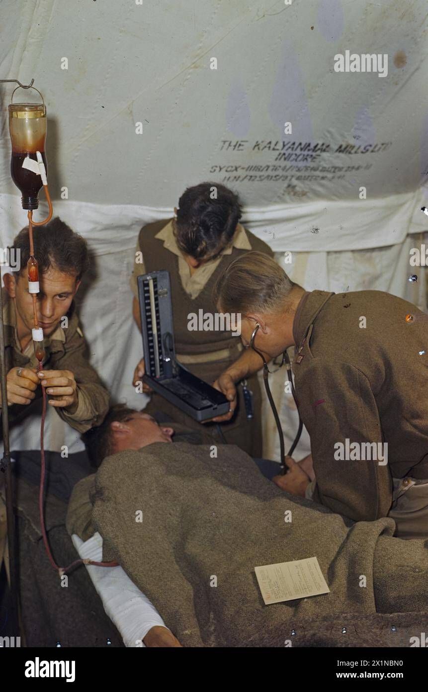 In Italia, nel 1944, un paziente ferito a una gamba riceve una trasfusione di sangue presso un'unità trasfusionale di campo prima di essere trasferito in una stazione di medicazione avanzata, con la pressione sanguigna monitorata durante l'intera procedura. Foto Stock