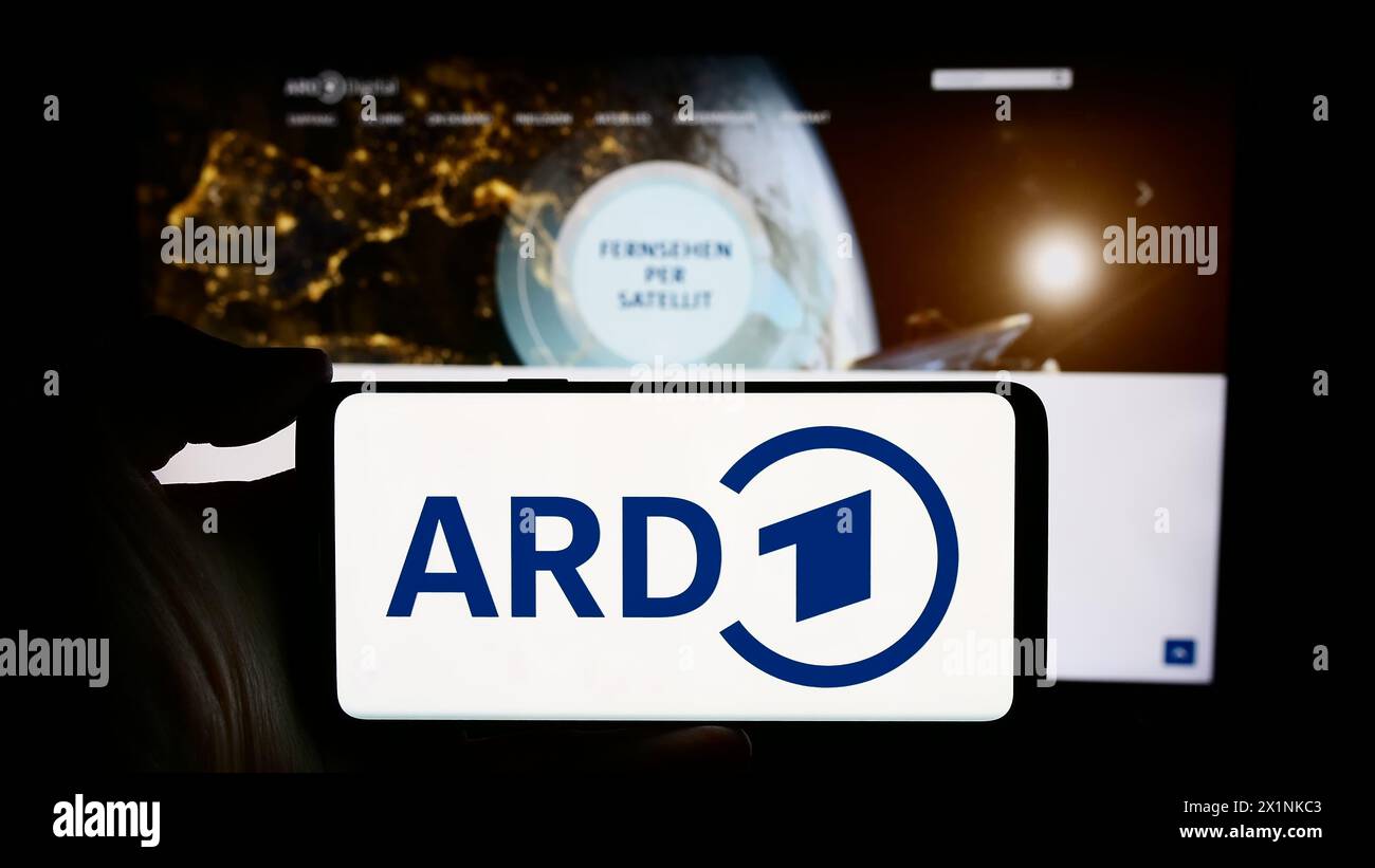 Persona che detiene un cellulare con il logo dell’organismo tedesco di radiodiffusione pubblica ARD davanti alla pagina web. Mettere a fuoco il display del telefono. Foto Stock