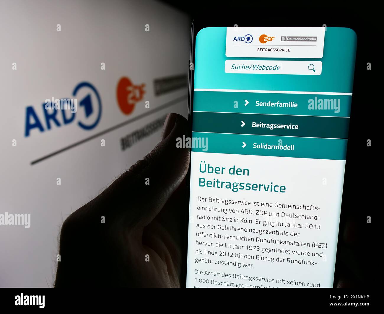 Persona che detiene un cellulare con il sito web di ARD ZDF Deutschlandradio Beitragsservice davanti al logo. Messa a fuoco al centro del display del telefono. Foto Stock