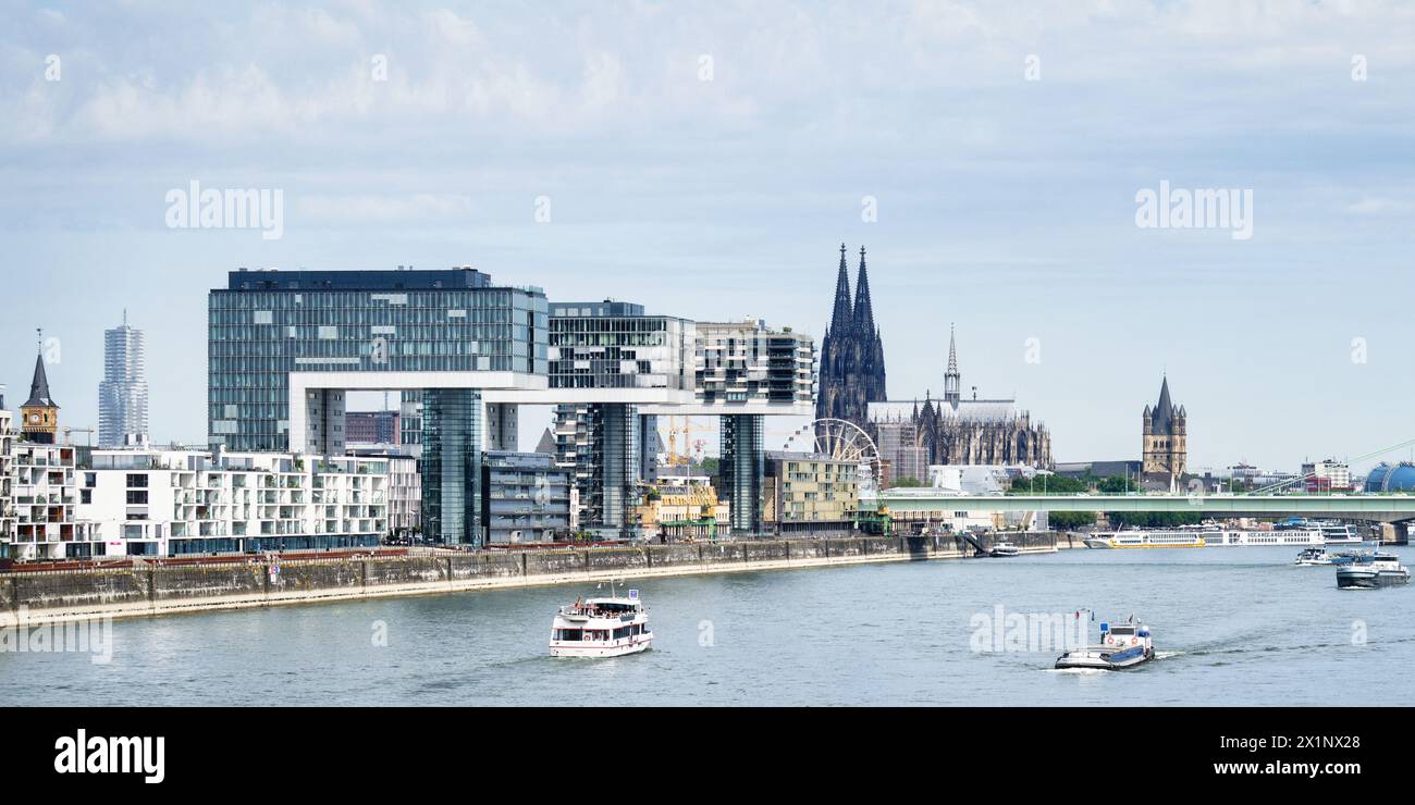 Colonia, Germania 18 luglio 2023: Escursione e navi cargo sul reno di fronte all'impressionante panorama di colonia con le gru e il gatto Foto Stock