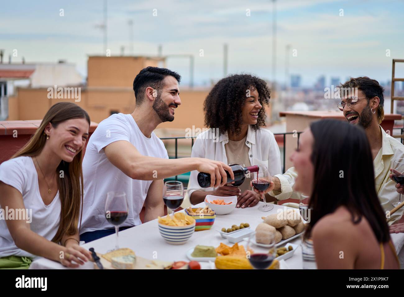 Gruppo di amici che si diverte a ridere insieme per una festa sulla terrazza sul tetto Foto Stock
