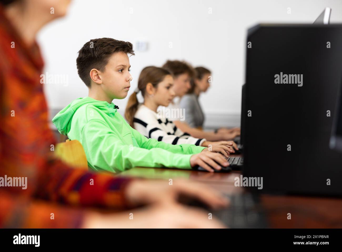 Ha messo a fuoco il ragazzo di Tween che studia con i compagni di classe in laboratorio del calcolatore Foto Stock