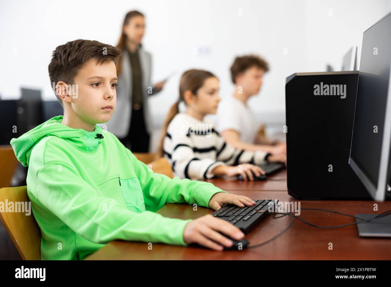 Ha messo a fuoco il ragazzo di Tween che studia con i compagni di classe in laboratorio del calcolatore Foto Stock