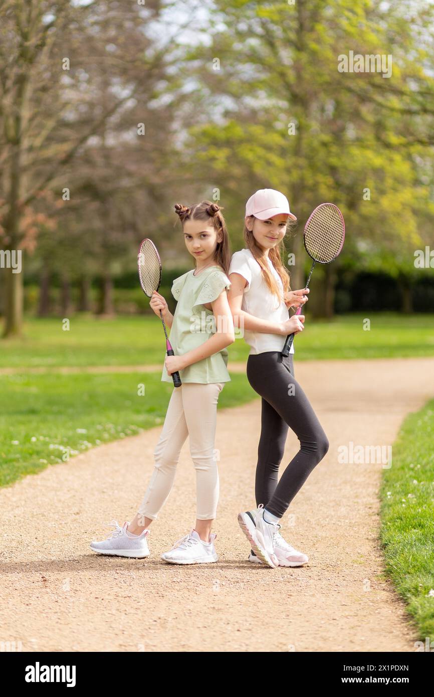 Due ragazze in posa con racchette da badminton nel parco. Foto Stock
