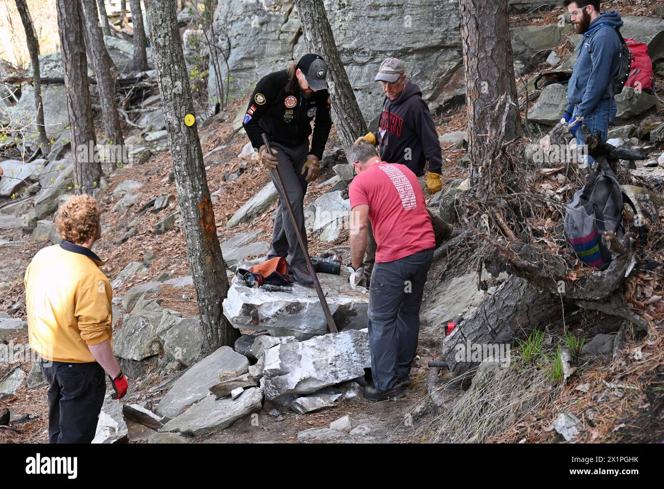 Un equipaggio addetto alla manutenzione dei sentieri lavora per rimuovere una grande roccia che è caduta dalla scogliera sul sentiero sottostante al Pilot Mountain State Park nel North Carolina. Foto Stock