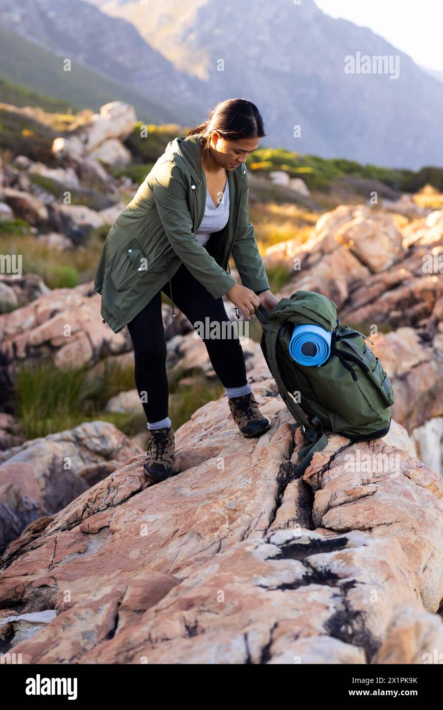 Escursionista birazziale donna che si adatta a un terreno roccioso in mezzo alla natura Foto Stock