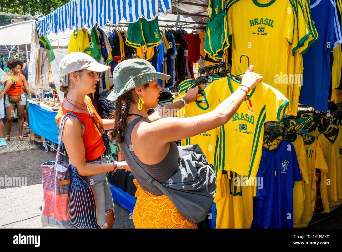 Due giovani donne scelgono le camicie da calcio brasiliane al mercato domenicale di Ipanema (Fiera Hippie), Rio de Janeiro, Stato di Rio de Janeiro, Brasile. Foto Stock