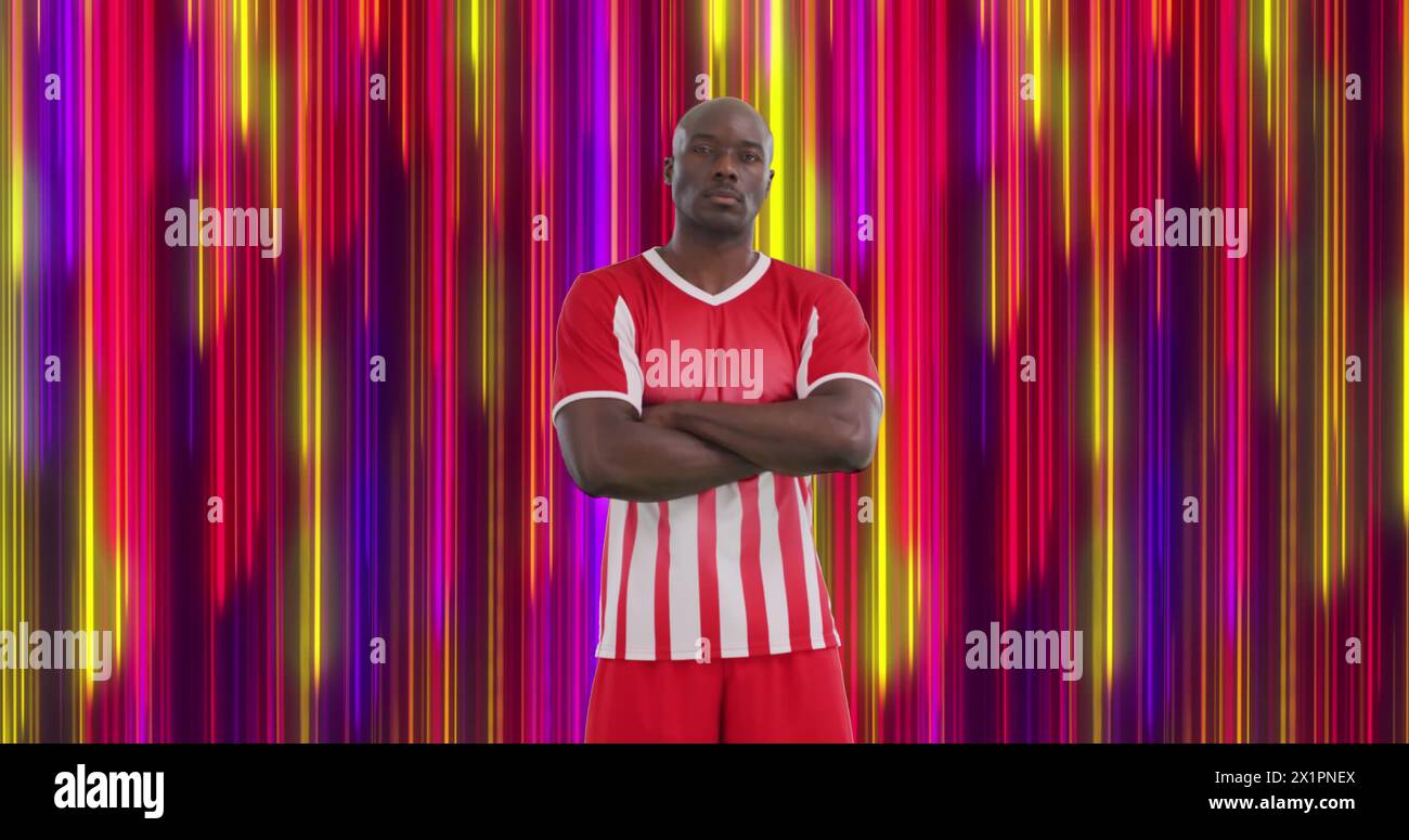 Uomo in uniforme sportiva rossa e bianca in piedi con le braccia incrociate, sembra serio Foto Stock
