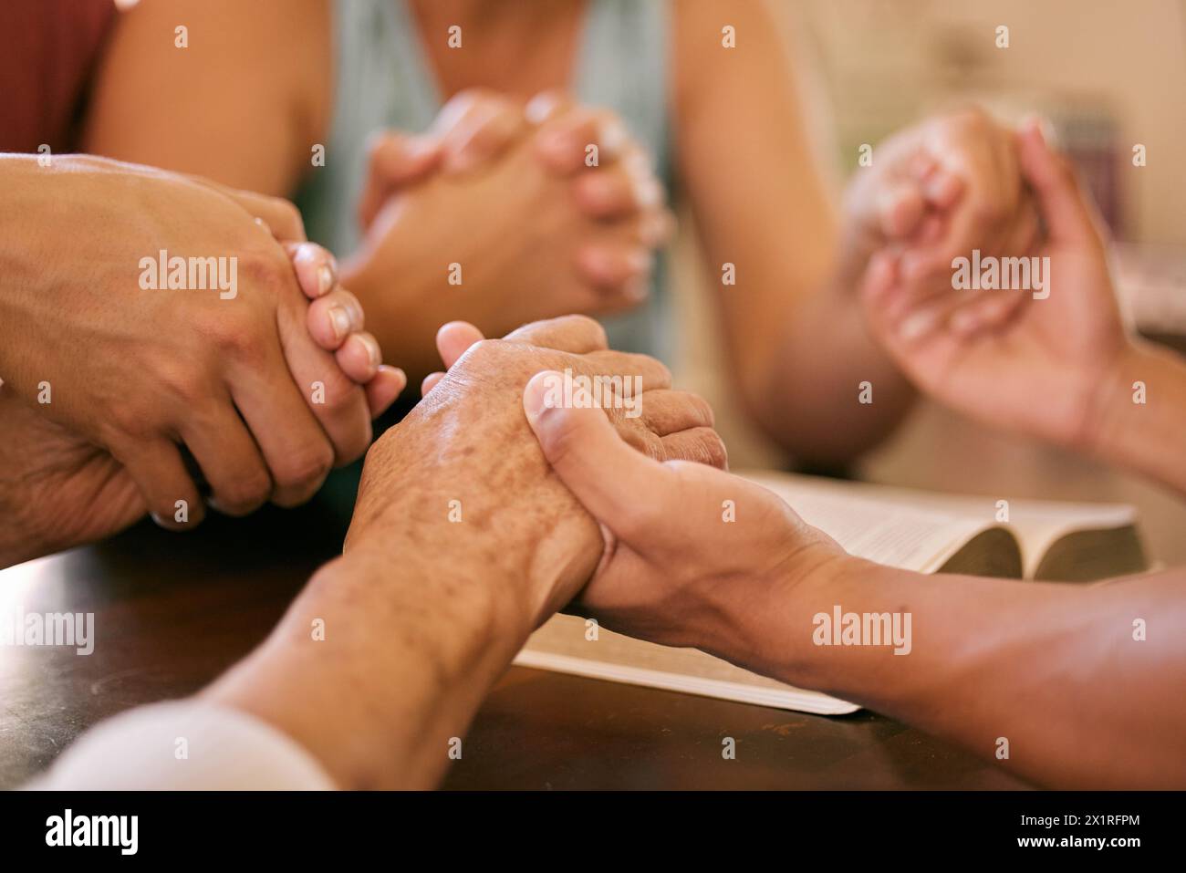 La Bibbia, Dio o la famiglia si tengono per mano nella preghiera per la pace, la fiducia o l'aiuto, la guida o la guarigione spirituale a casa. Adorazione, chiesa o comunità in preghiera Foto Stock
