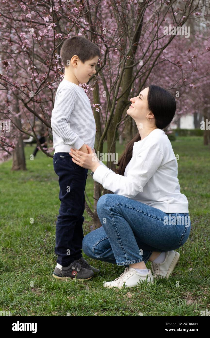 Mamma e figlio di sei anni nel giardino fiorito in primavera. Foto Stock