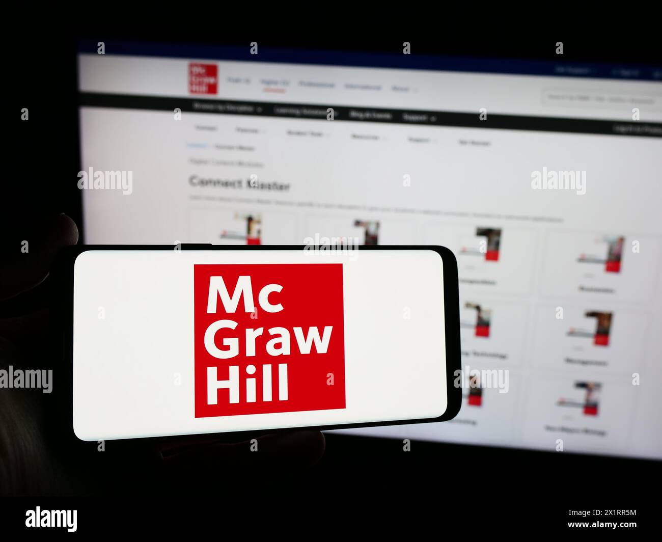 Persona che detiene uno smartphone con il logo della casa editrice statunitense McGraw Hill LLC davanti al sito Web. Mettere a fuoco il display del telefono. Foto Stock