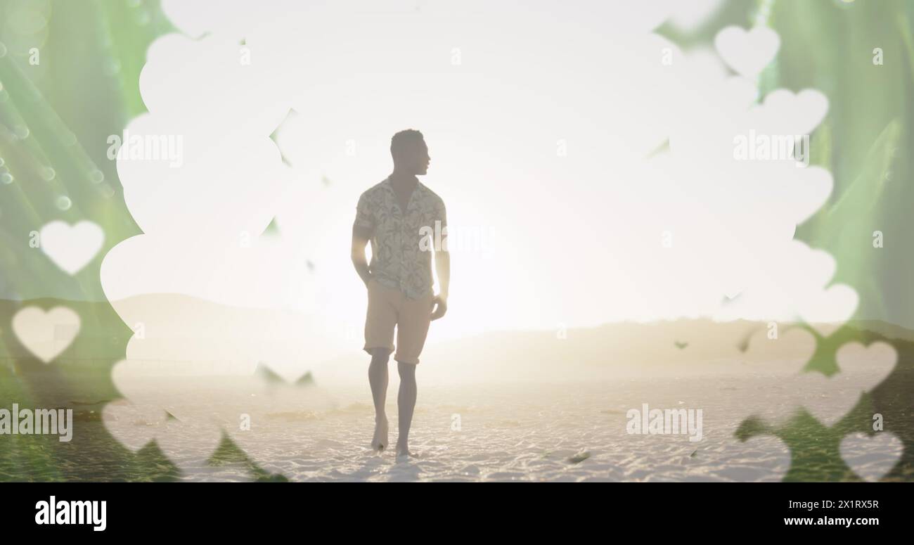 Un giovane afro-americano in piedi sulla spiaggia al tramonto Foto Stock