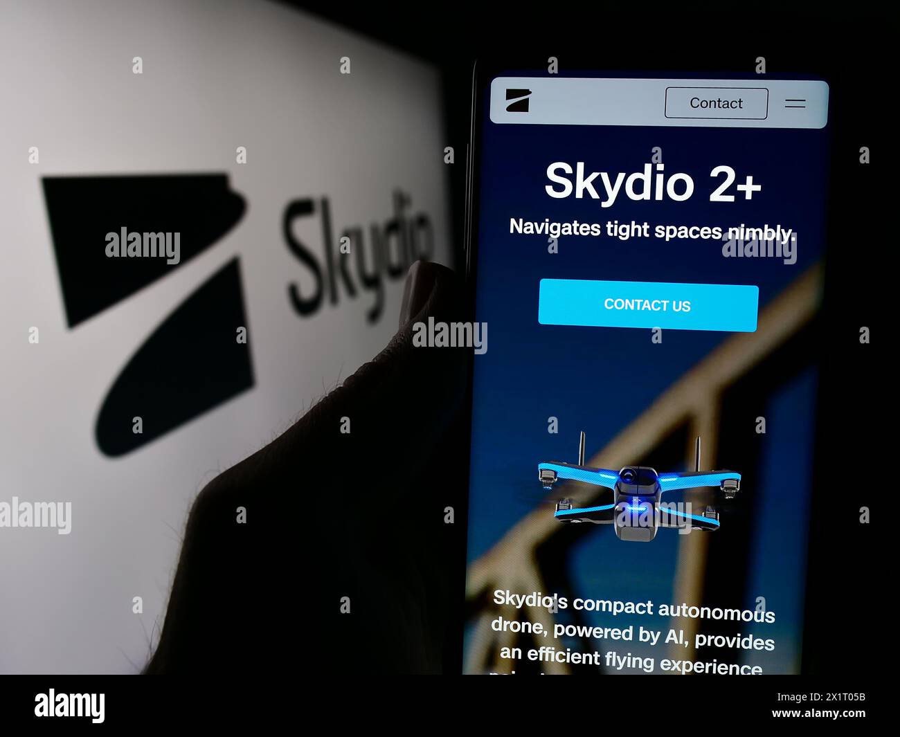 Persona che detiene un cellulare con pagina web della società di produzione di droni Skydio Inc. Davanti al logo aziendale. Messa a fuoco al centro del display del telefono. Foto Stock