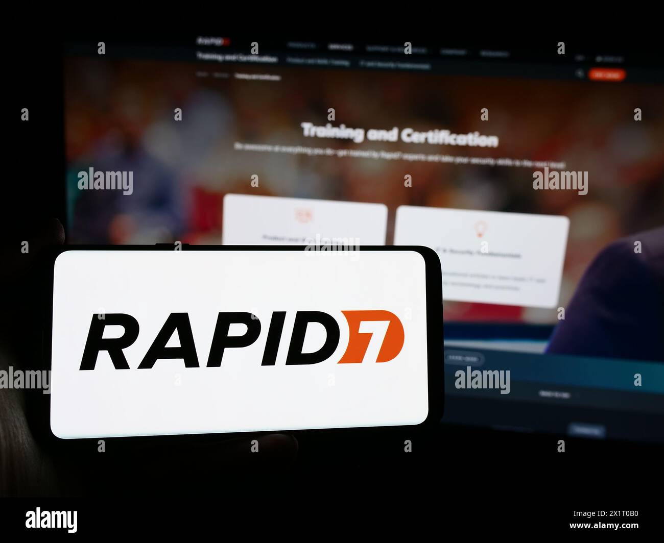 Persona che possiede uno smartphone con il logo della società statunitense di sicurezza informatica Rapid7 davanti al sito web. Mettere a fuoco il display del telefono. Foto Stock