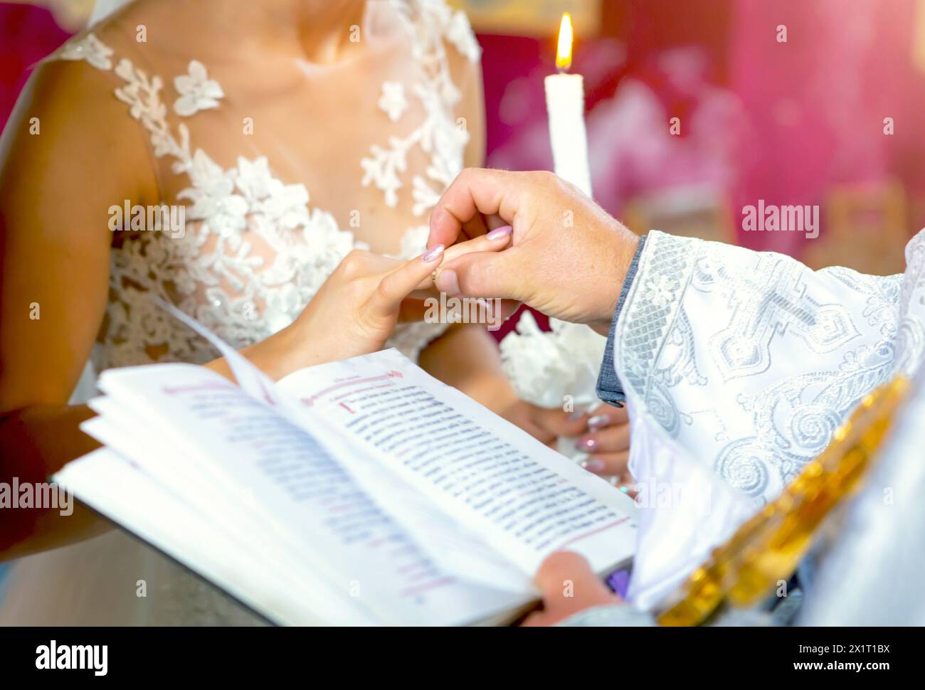 scambio di fedi nuziali. prete che indossa le fedi nuziali dorate su dita sposa e sposo in chiesa al matrimonio. tradizione religiosa Foto Stock