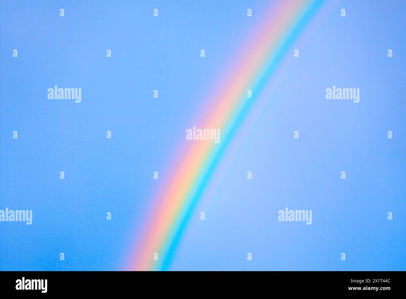 Arco arcobaleno vibrante attraverso il cielo blu brillante. Incredibile contrasto di colori Foto Stock