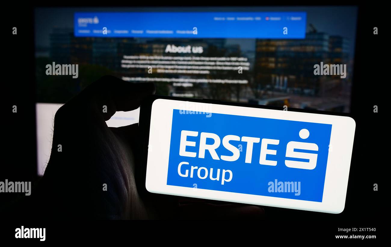 Persona che detiene lo smartphone con il logo della società austriaca di servizi finanziari Erste Group Bank AG davanti al sito web. Mettere a fuoco il display del telefono. Foto Stock
