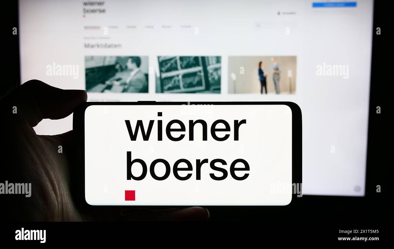 Persona che detiene un cellulare con il logo della società austriaca di borsa Wiener Börse AG davanti alla pagina web aziendale. Mettere a fuoco il display del telefono. Foto Stock