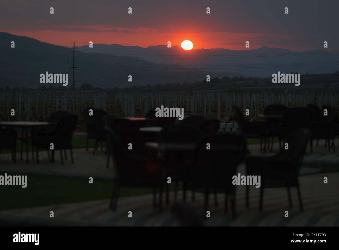 Il sole tramonta sulle colline con un vigneto in primo piano. Foto Stock