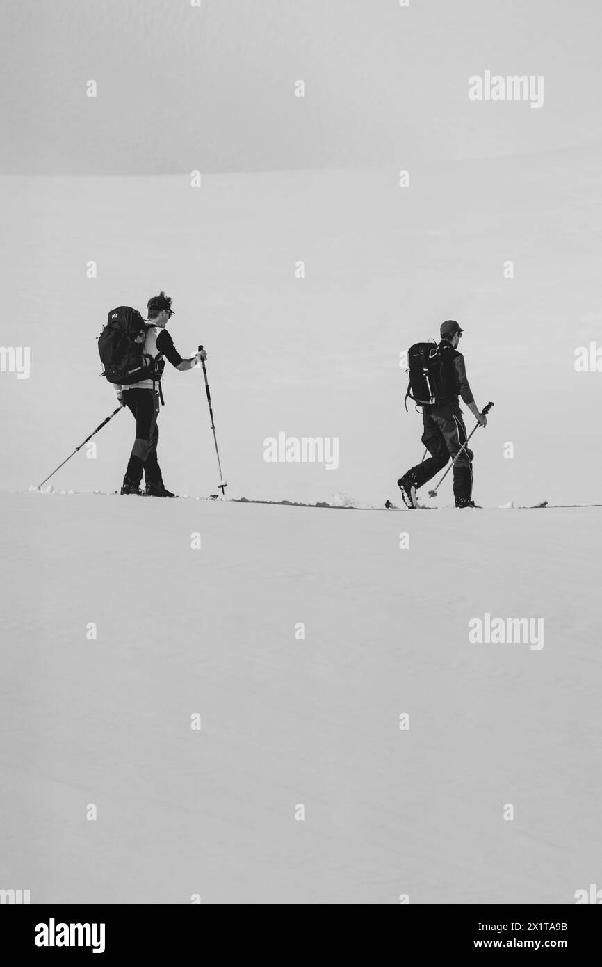 Atleti che praticano sci di fondo con un paesaggio di montagne innevate in una giornata di sole. Tramonto sulle montagne innevate. Foto Stock