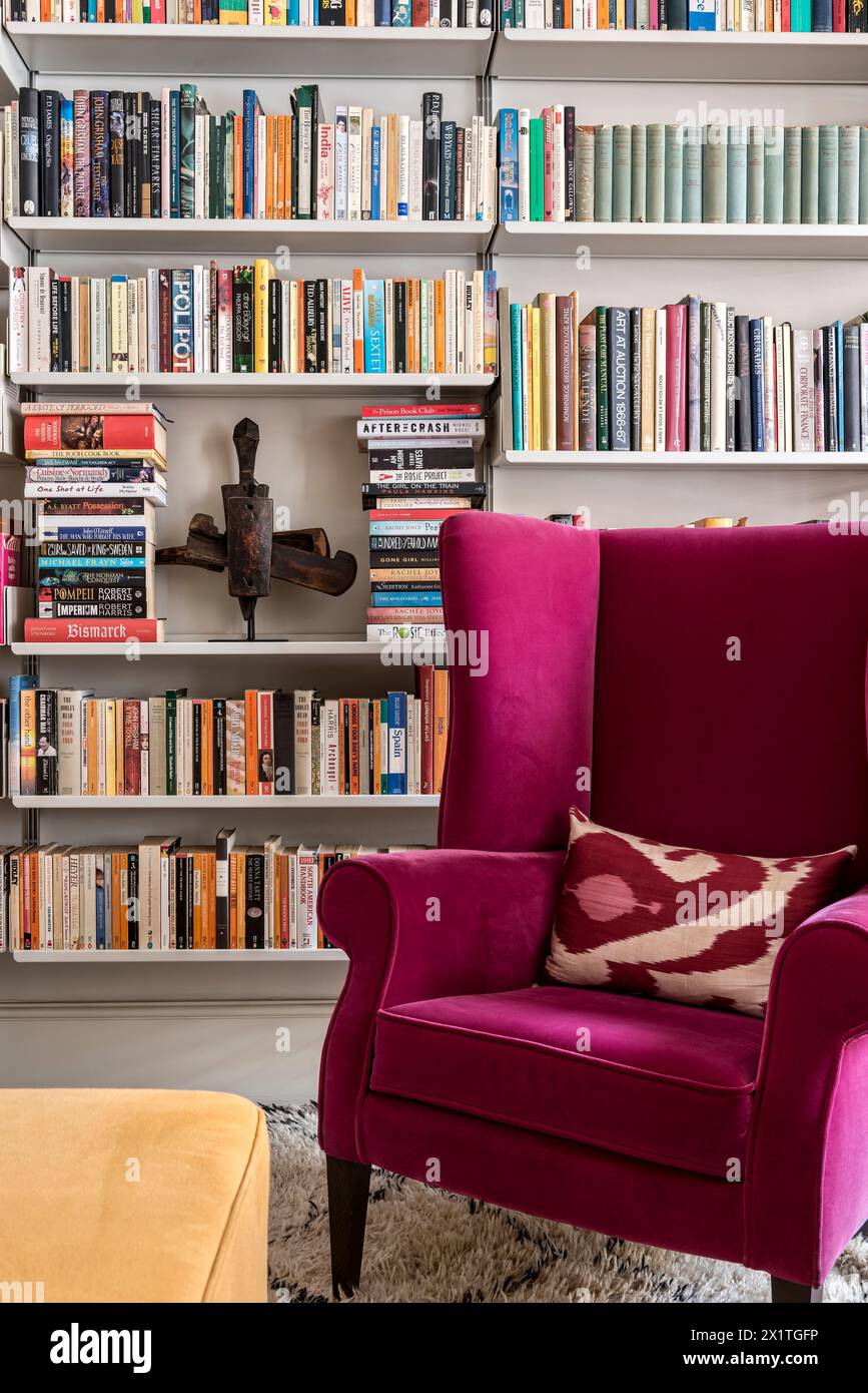 Poltrona rosa con scaffali di libri a Chelsea home, Londra, Regno Unito Foto Stock