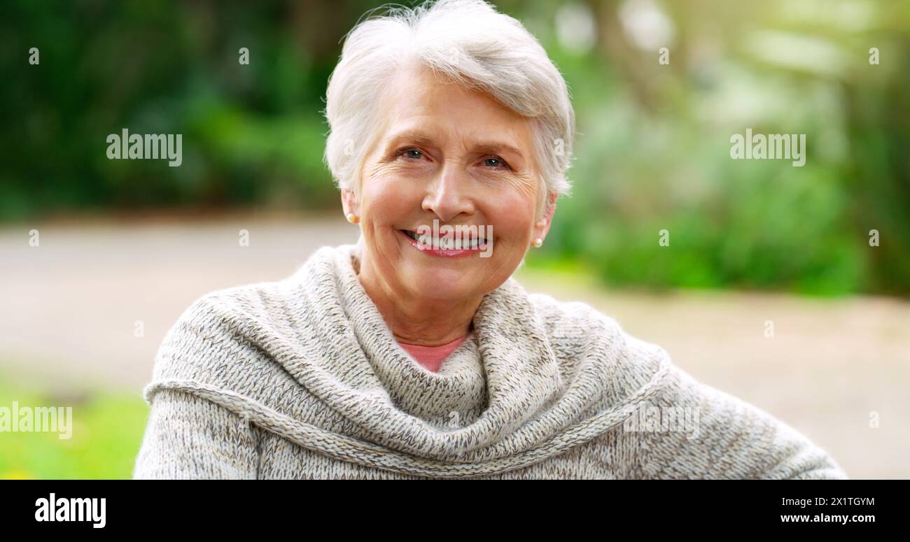 Parco, felice e ritratto di donna anziana in natura per il sole, l'ambiente e la pensione. Persona anziana, rilassati e sorridi nel giardino della casa di cura Foto Stock