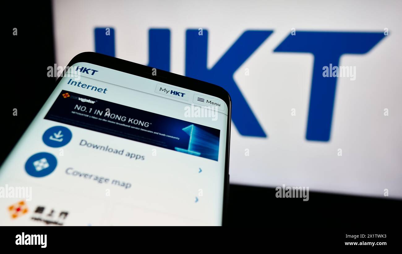 Telefono cellulare con sito web della società di telecomunicazioni HKT Limited (Hong Kong Telecom) davanti al logo. Mettere a fuoco in alto a sinistra sul display del telefono. Foto Stock