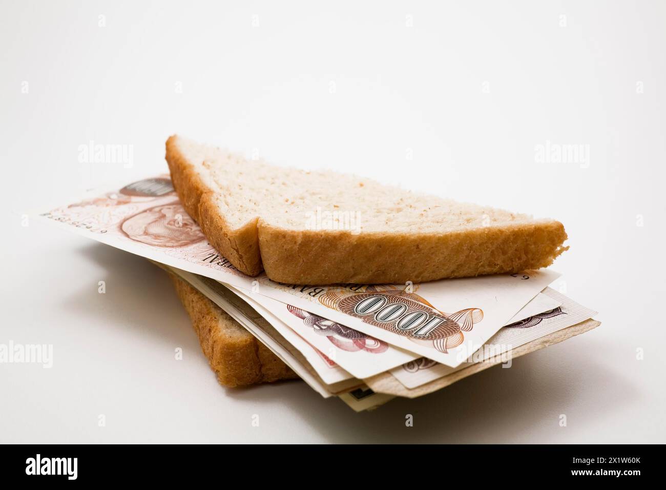 Primo piano di pane integrale mezzo sandwich ripieni di banconote in valuta estera su sfondo bianco, Studio Composition, Quebec, Canada Foto Stock