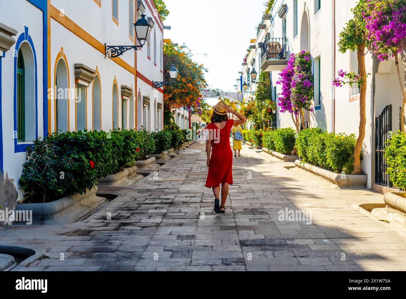 Una donna che cammina nel porto della città costiera fiorita di Mogan, nel sud di Gran Canaria. Spagna Foto Stock