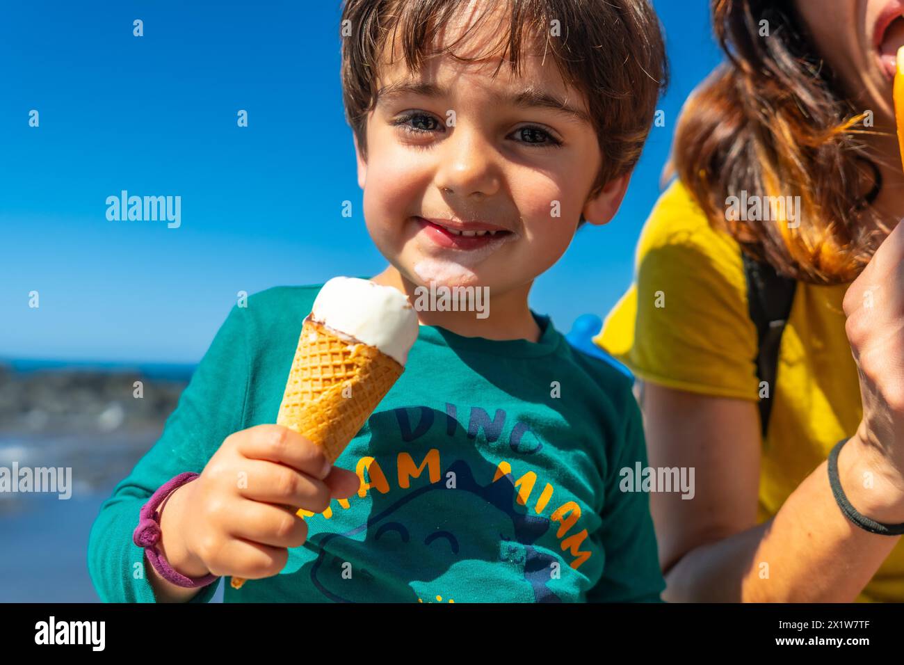 Mamma con il suo bambino si godeva le vacanze estive sorridendo mangiando gelato in riva al mare Foto Stock