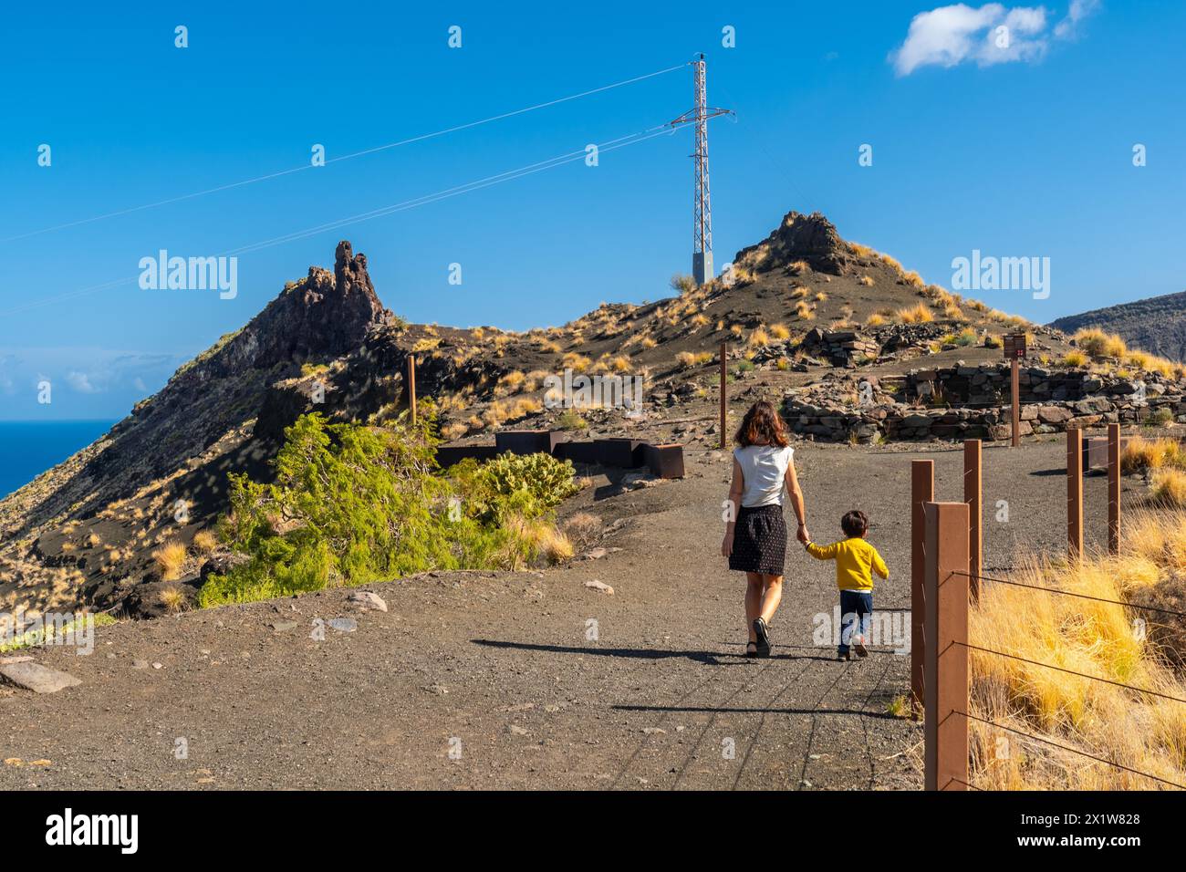 Una madre e suo figlio camminano lungo la formazione rocciosa sulla costa di Agaete, Roque Guayedra, Gran Canaria Foto Stock