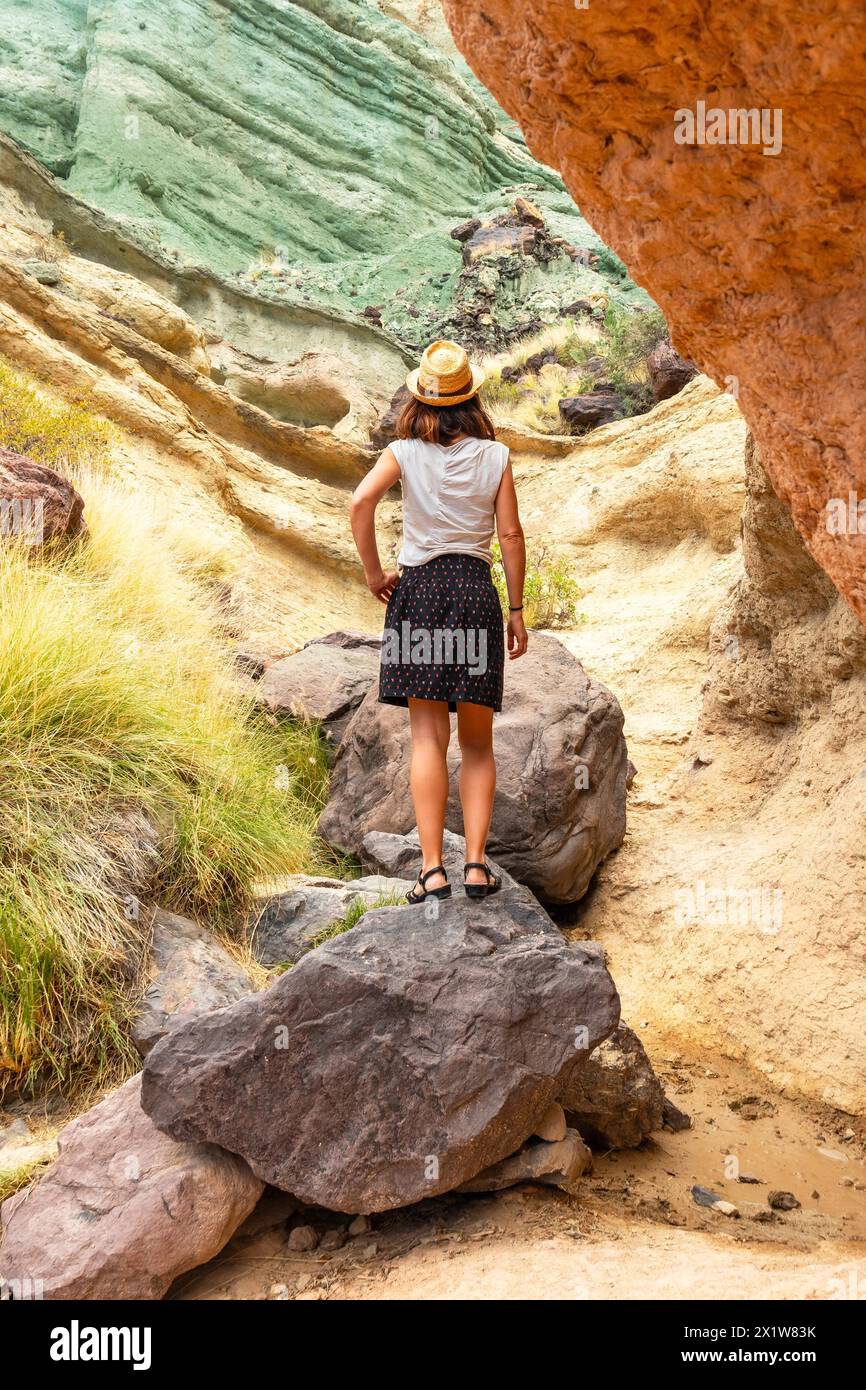 Una donna turistica con un cappello all'Azulejos de Veneguera o Rainbow Rocks a Mogan, Gran Canaria Foto Stock