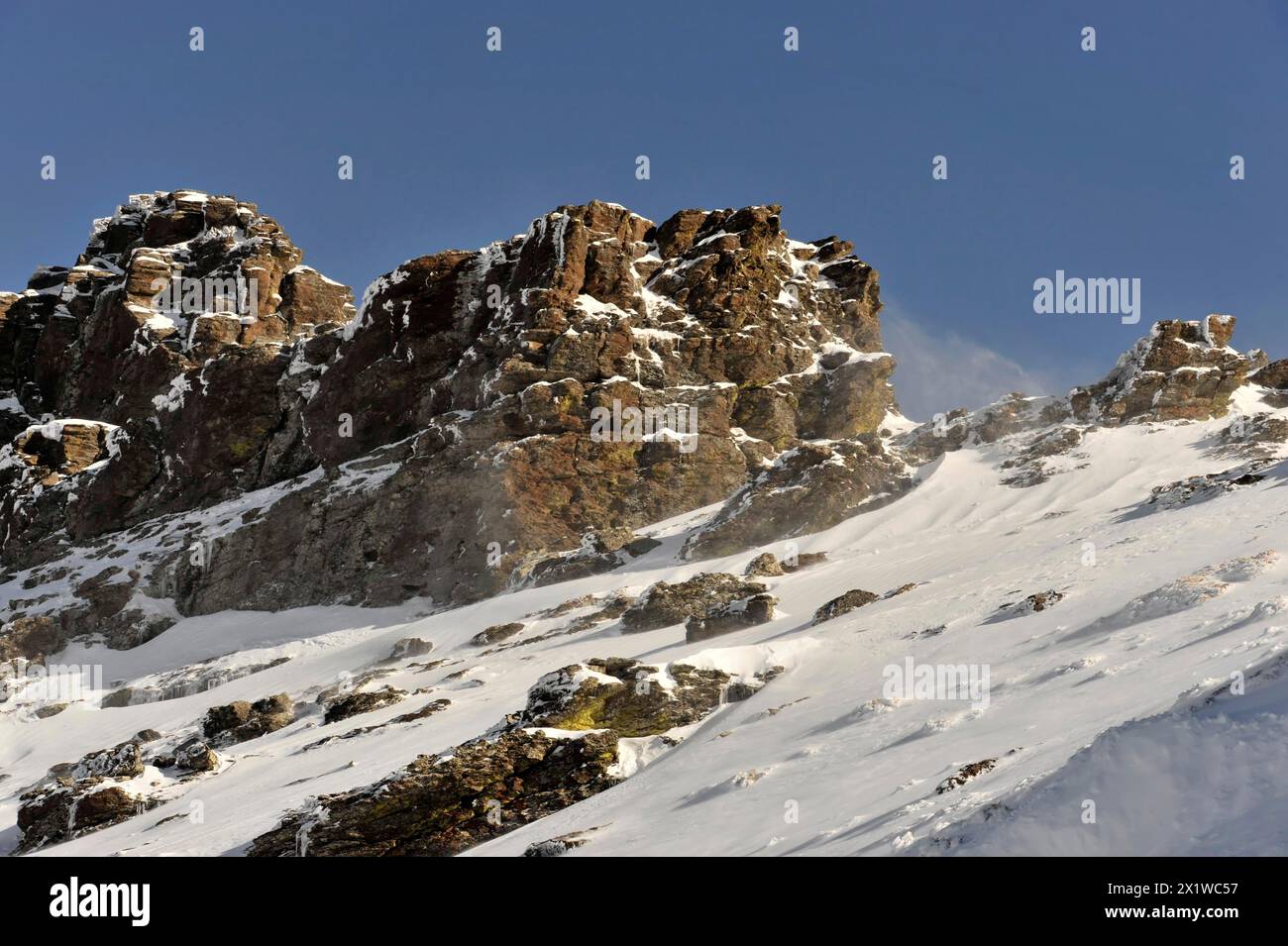 Montagne in Andalusia, catena montuosa innevata, vicino a Pico del Veleta, 3392 m, Gueejar-Sierra, Parco Nazionale della Sierra Nevada, da cui sorgono rocce robuste Foto Stock