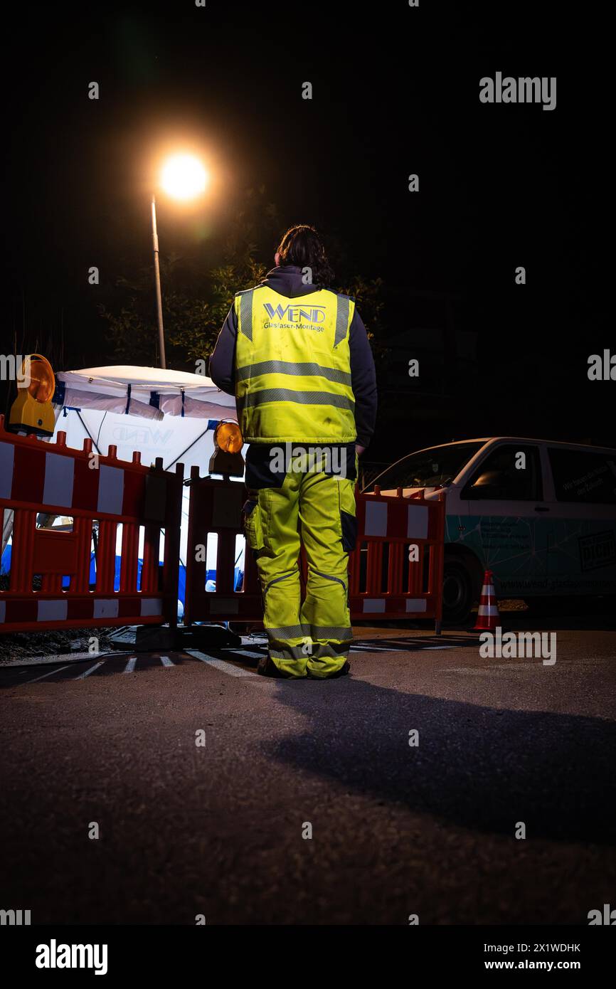 La persona che indossa indumenti di sicurezza monitora un cantiere durante la notte sotto la luce artificiale, Galsfaserbau, Calw, Foresta Nera, Germania Foto Stock