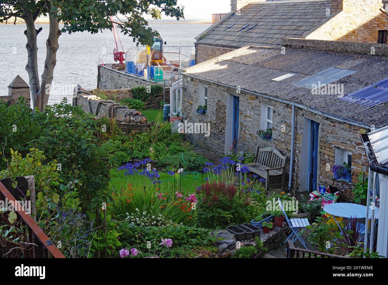 Giardini tranquilli e idilliaci di fronte a una piccola casa in pietra, Stromness, Isole Orcadi, Scozia, Regno Unito Foto Stock