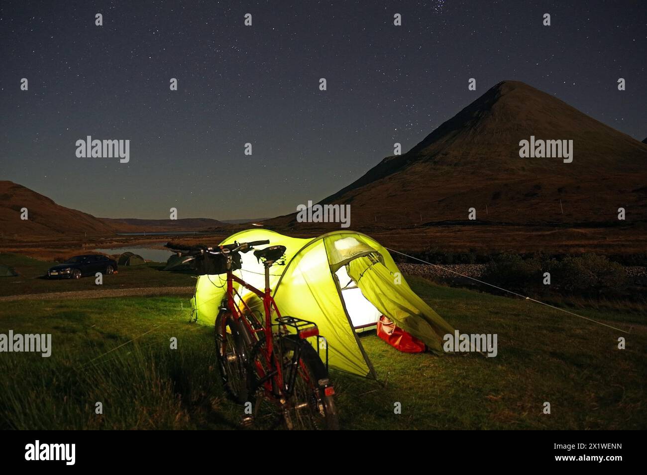 Tenda illuminata con una torcia di fronte alle aspre montagne, bicicletta, Cullins, Isola di Skye, Ebridi, Scozia, Gran Bretagna Foto Stock