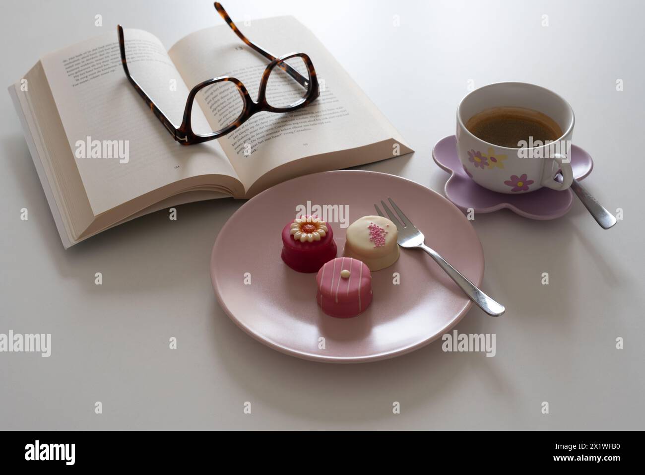 Il tempo per una pausa con una tazza di caffè, un buon libro e deliziosi petits fours di marzapane è pura felicità Foto Stock