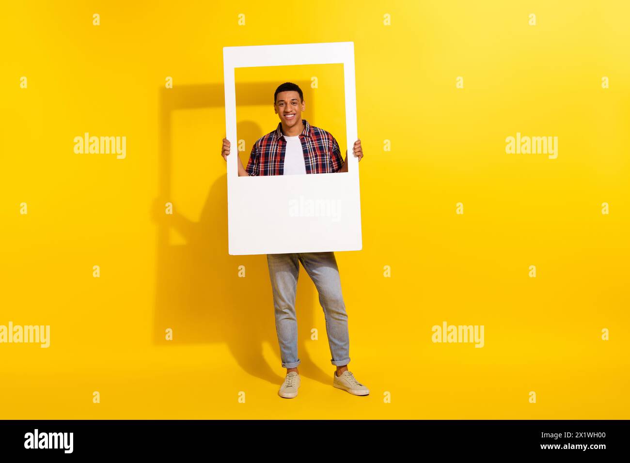 Foto a grandezza naturale di splendidi jeans a quadri con montatura bianca e mani isolate su sfondo giallo Foto Stock