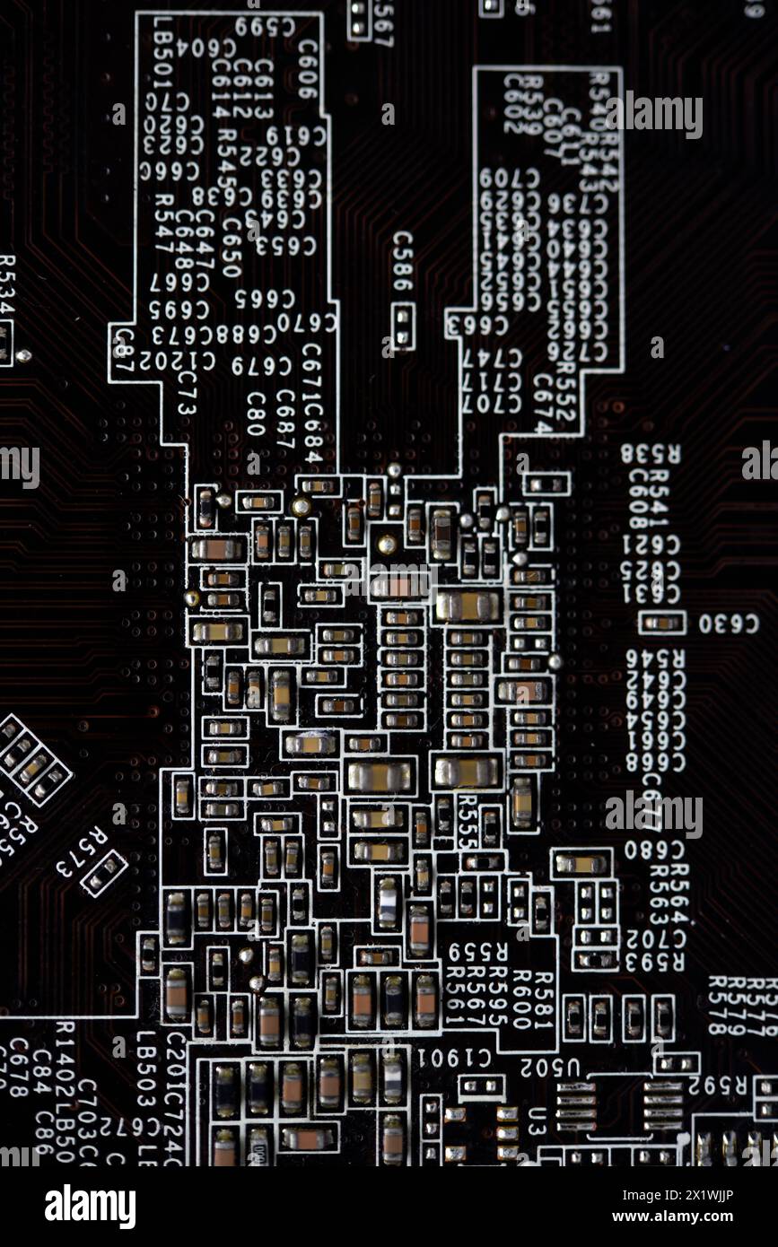 Una scheda a circuito stampato marrone con resistori e condensatori. Una scheda elettronica con elementi radio. Foto Stock