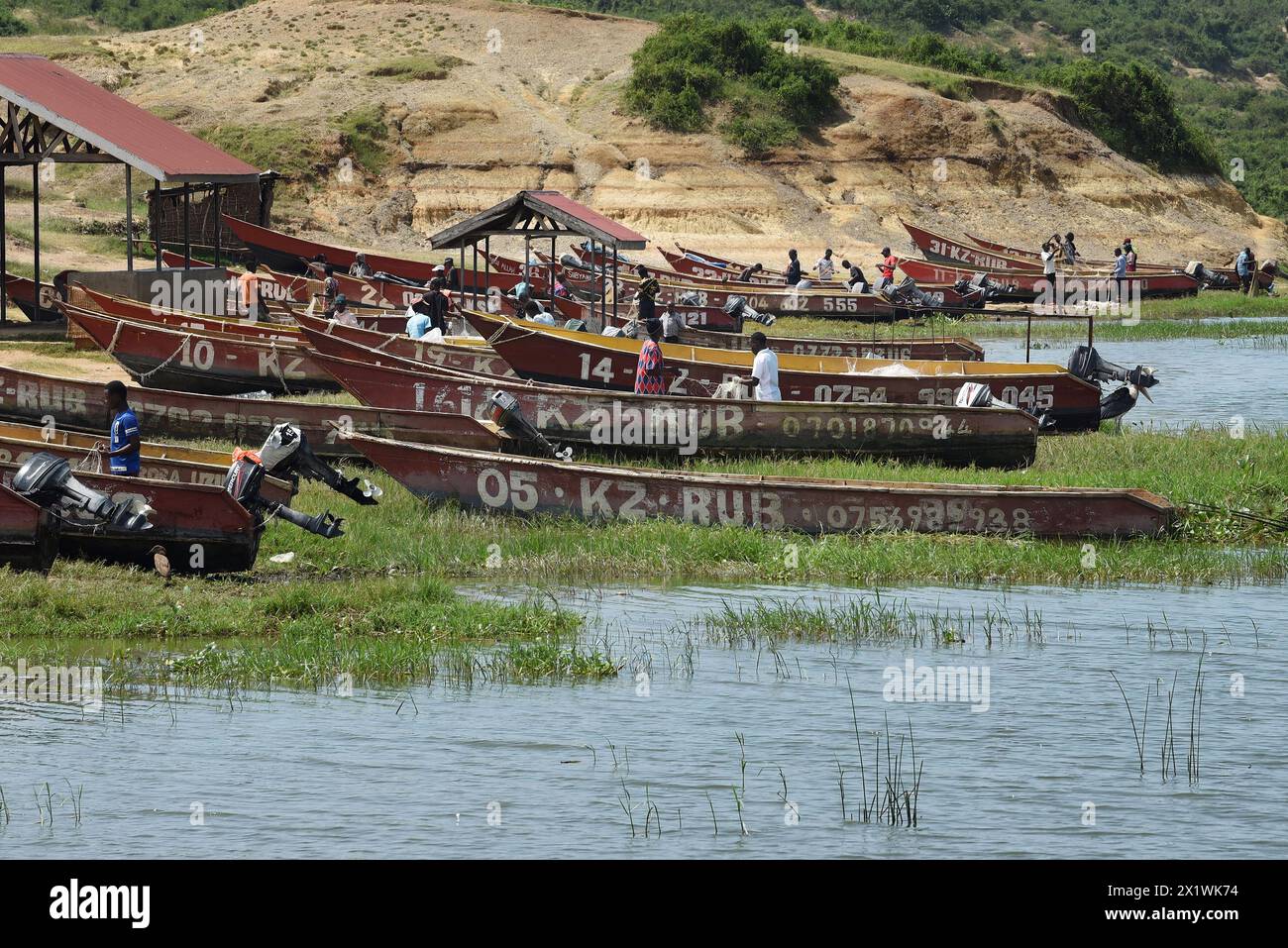 I pescatori preparano meticolosamente le loro canoe motorizzate lungo le tranquille acque del canale di Kazinga, assicurandosi che tutte le attrezzature siano pronte prima dell'imbarco Foto Stock