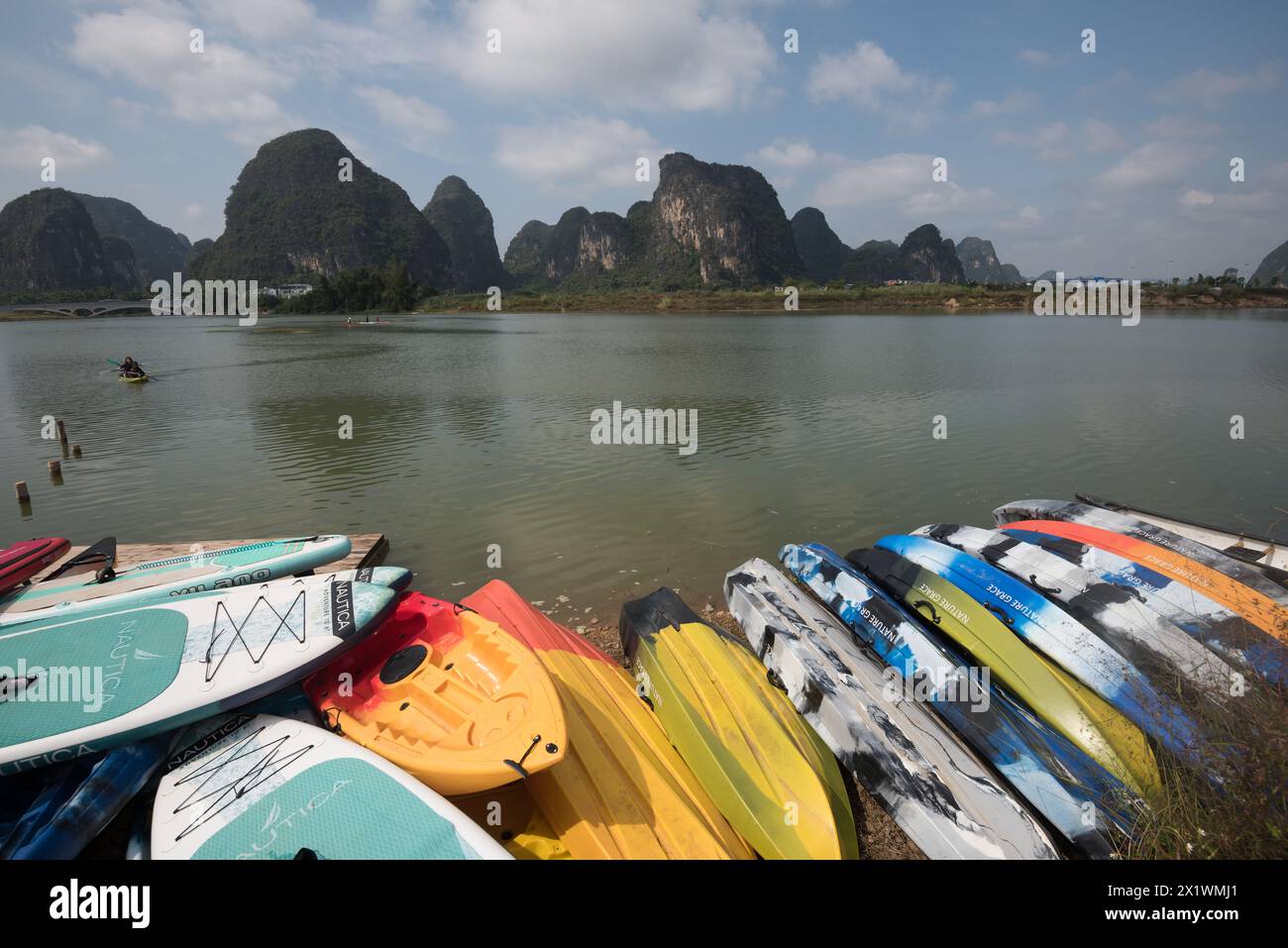 Yangshuo County, Guilin City, Guangxi, Cina - 28 ottobre 2023: Tavole da paddle e canoe sul lungomare per i turisti per godersi le attività ricreative in acqua Foto Stock