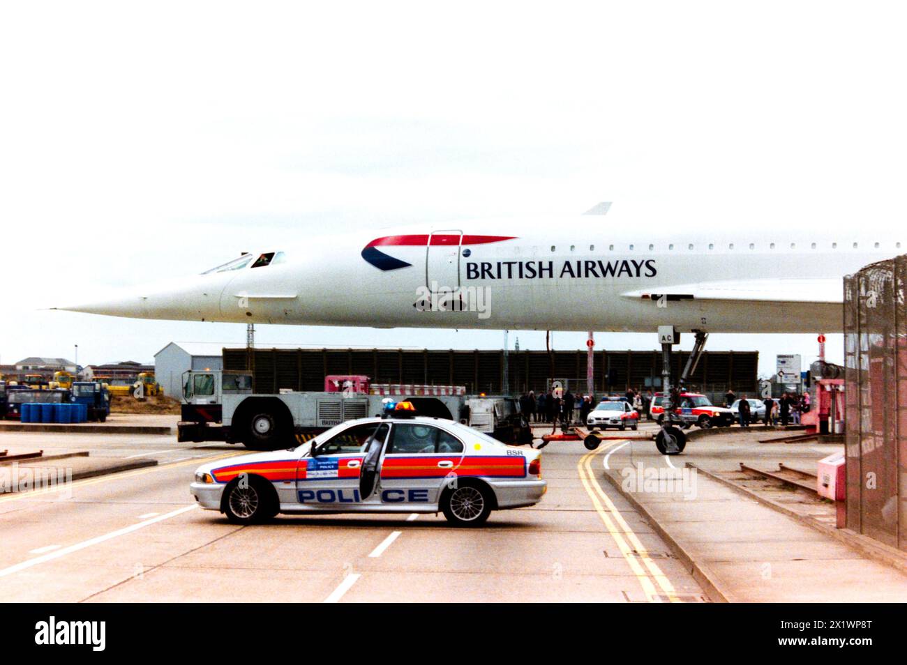 La British Airways BAC Concorde G-BOAC viene trainata attraverso Eastchurch Road all'aeroporto di Londra Heathrow, con la strada chiusa dalla polizia. La flotta di BA Concorde era parcheggiata nel loro hangar di manutenzione sul perimetro dell'aeroporto e trainata nell'area interna dell'aeroporto quando era necessario operare voli di linea. Gli appassionati si sono riuniti per vedere Concorde verso la fine del suo servizio che richiedeva una maggiore presenza della polizia. Volò per la prima volta come G-BOAC nel 1975. Consegnato alla British Airways nel 1976. Volò a Manchester per la conservazione e l'esposizione il 31 ottobre 2003 Foto Stock