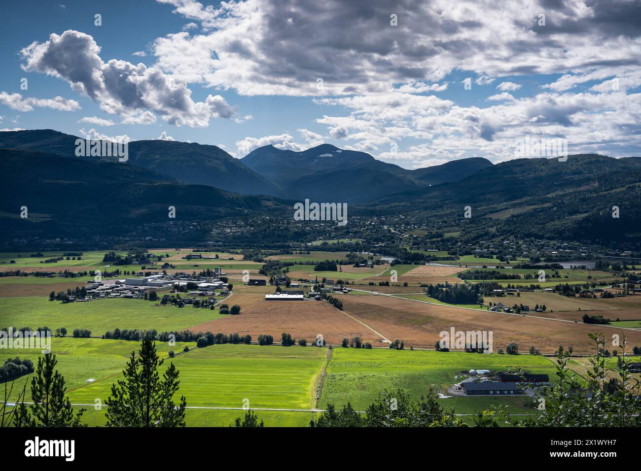 Vista ad alto angolo dei villaggi rurali agricoli Sylte e Skei a Surnadal, Norvegia, con le montagne del Surnadalsfjord con un po' di neve lasciata sullo sfondo Foto Stock