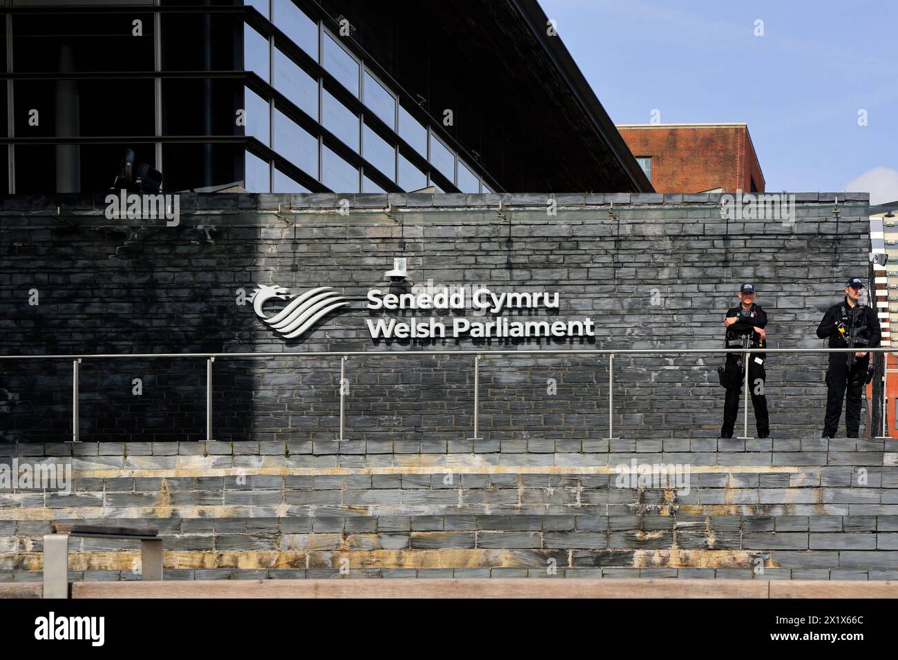 Edificio del Parlamento gallese con due poliziotti armati a guardia dell'ingresso. Preso nell'aprile 2024 Foto Stock