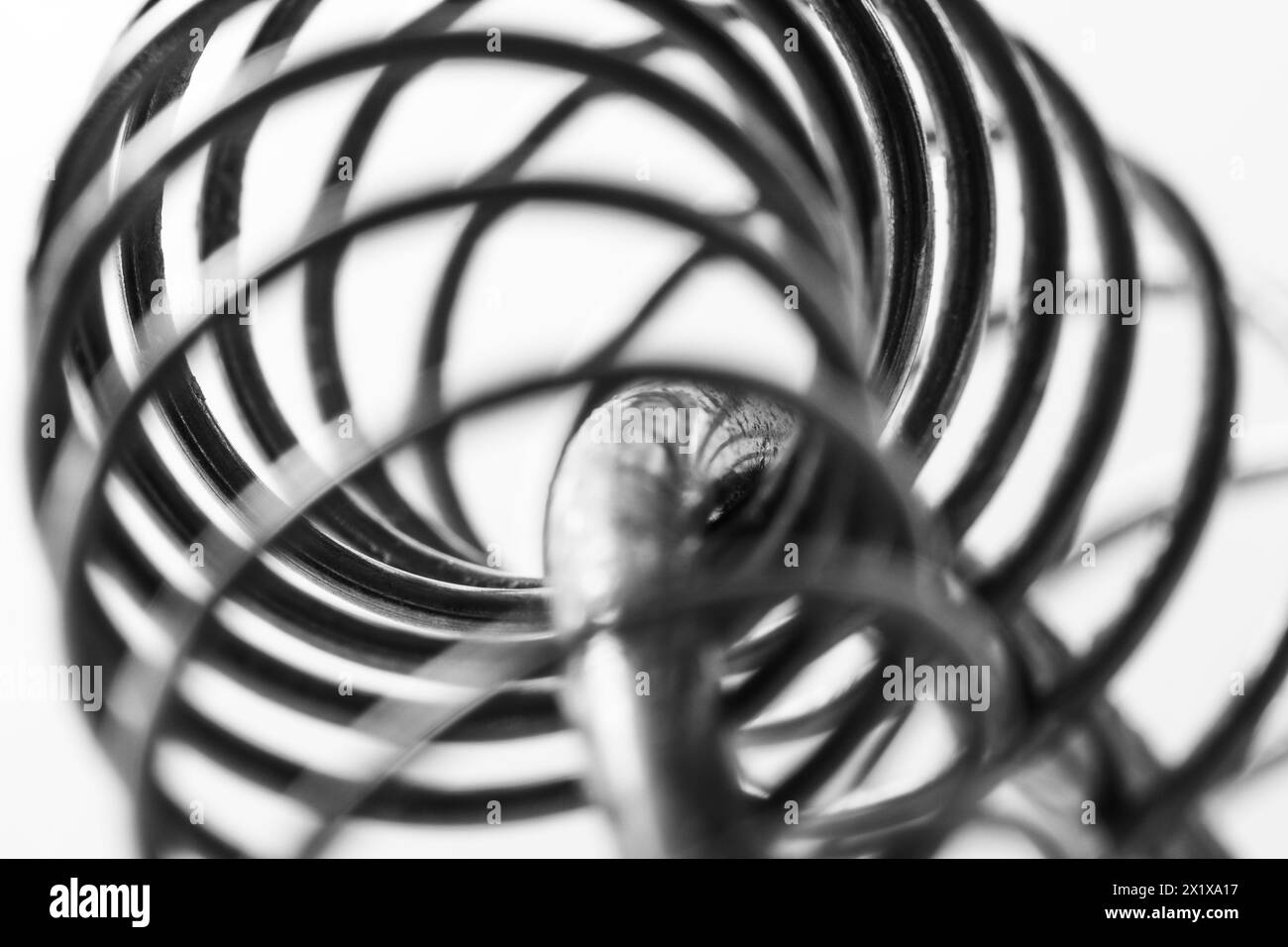 Spirale a molla in metallo, macro shot in bianco e nero, messa a fuoco morbida, arte industriale astratta Foto Stock