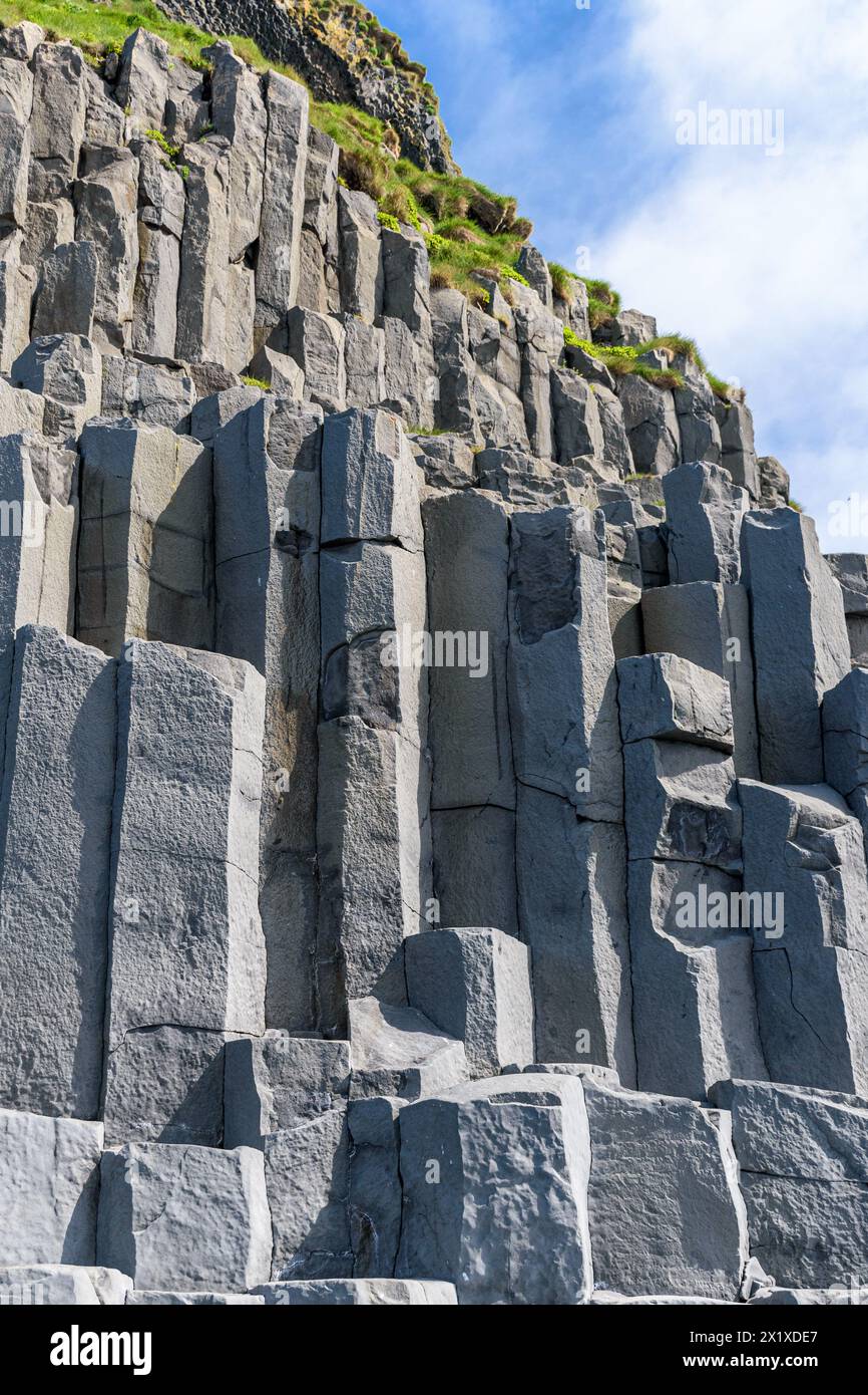 Colonne di basalto alla base della scogliera di Reynisfjall sulla spiaggia di Reynisfjara nella scogliera dell'Islanda meridionale Foto Stock