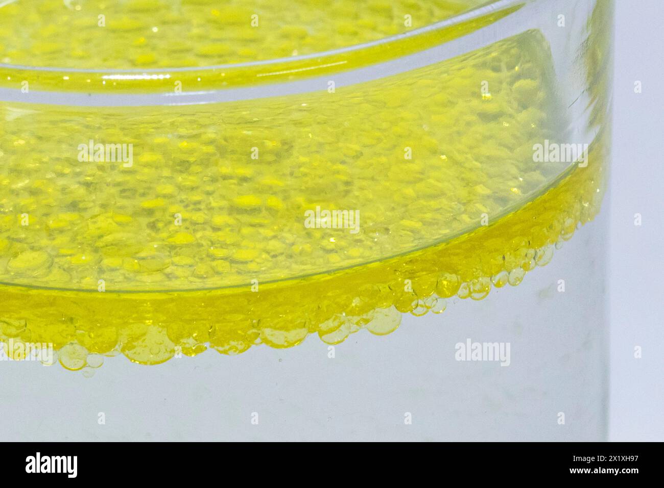 Olio miscelato in un bicchiere con acqua che indica che l'acqua e l'olio si separano con l'olio che galleggia verso la parte superiore Foto Stock