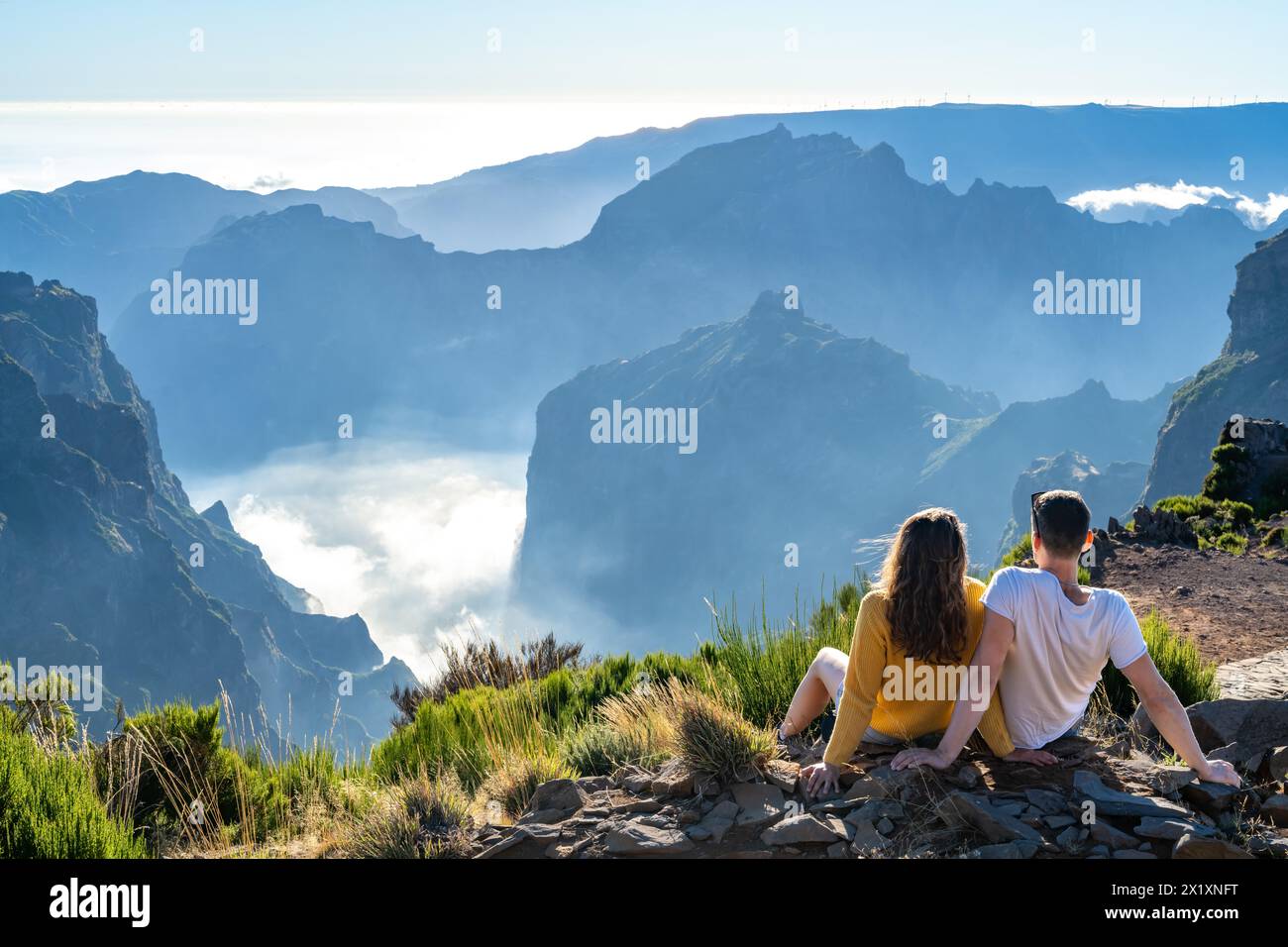 Descrizione: Una coppia di turisti gode di una vista pittoresca dalla cima di un'isola vulcanica in una soleggiata giornata estiva. Pico do Arieiro, Madeira ISL Foto Stock